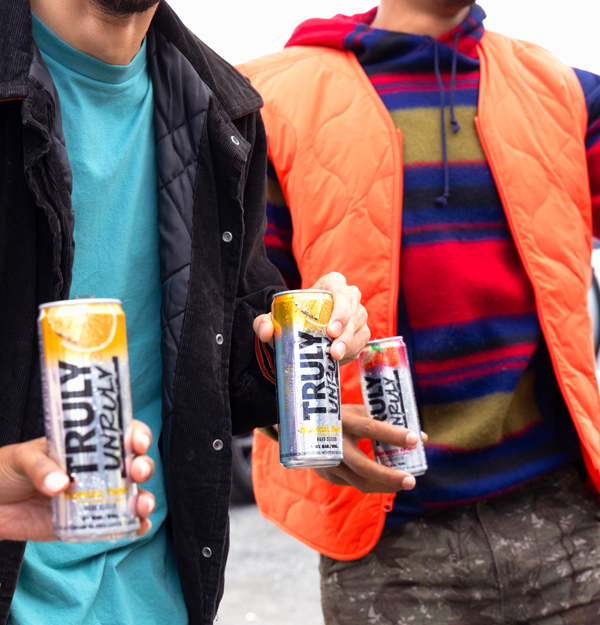 Three people holding cans of Truly Unruly